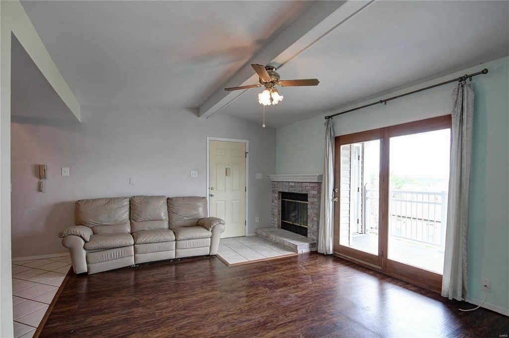 Living room with wood-burning brick fireplace and sliding door to the covered deck