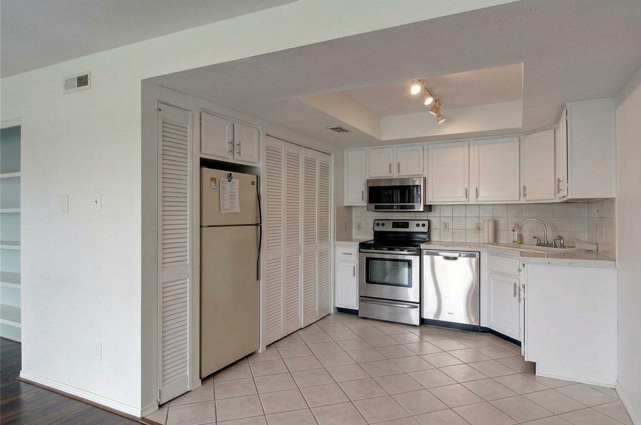 Kitchen with stainless steel range, microwave and dishwasher, white cabinets and tile floor